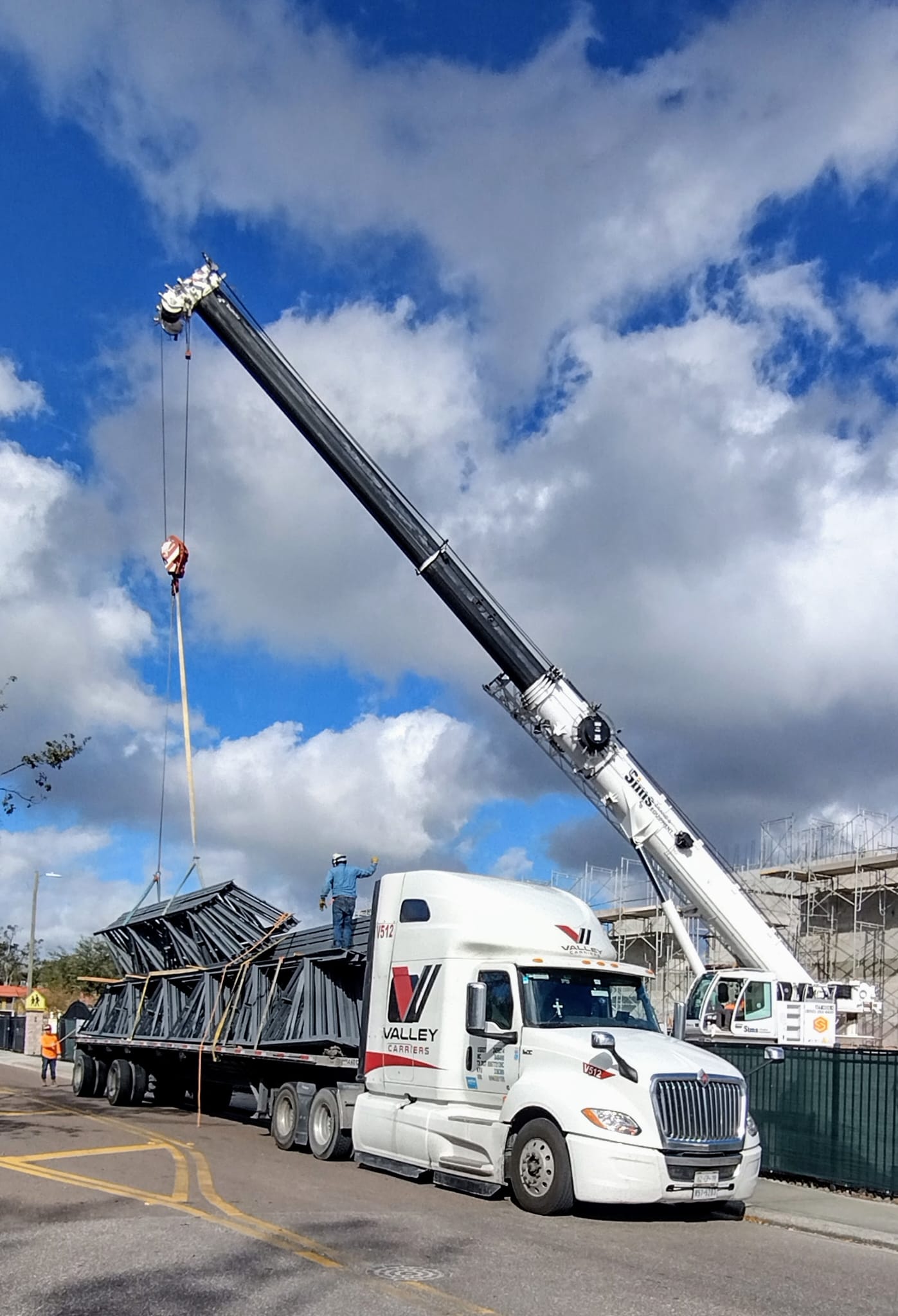 Steel joists lifted off a Valley Carriers flatbed by crane at the delivery site